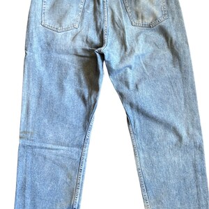May include: Light blue denim jeans with a brown leather patch on the back waistband that says "Wrangler".