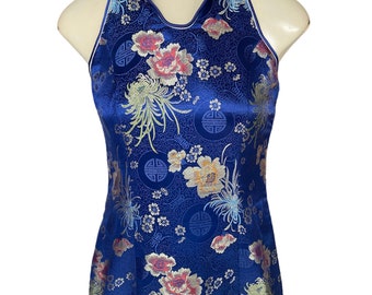 May include: A blue halter dress with a floral pattern and gold accents. The dress has a mandarin collar and a fitted silhouette.