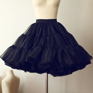 May include: A black tulle petticoat with multiple layers, creating a full and voluminous silhouette. The petticoat is displayed on a mannequin.