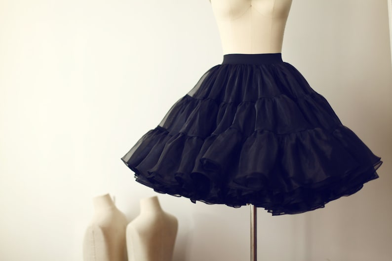 May include: A black tulle petticoat with multiple layers, creating a full and voluminous silhouette. The petticoat is displayed on a mannequin.