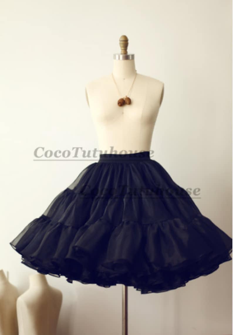 May include: Black tulle petticoat with multiple layers, creating a full, voluminous skirt. The petticoat is displayed on a mannequin and has a simple, classic design.