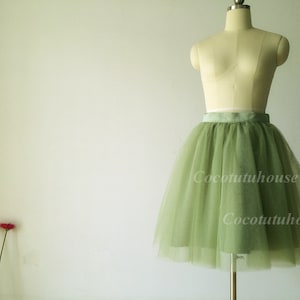 May include: A sage green tulle skirt with a satin waistband. The skirt is on a mannequin and is photographed against a white background.