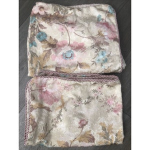 May include: Two cream-colored pillowcases with a floral pattern in shades of pink, blue, and brown. The pillowcases have a pink and gold trim.