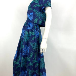 K&ouml;nnte beinhalten: Ein zweiteiliges Kleid mit blauem und gr&uuml;nem Blumendruck, bestehend aus einem Crop-Top und einem Midirock.