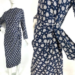 Puede incluir: Un vestido midi azul marino con estampado floral blanco. El vestido tiene un estilo de envoltura y un lazo en la cintura.