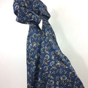 Puede incluir: Un vestido de estampado floral azul y marr&oacute;n con falda larga y mangas largas. El vestido tiene cuello y cierre de botones en la parte delantera.