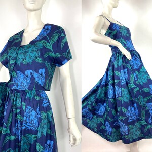 K&ouml;nnte beinhalten: Ein blaues und gr&uuml;nes Blumenkleid mit einer passenden kurzen Jacke. Das Kleid hat ein tailliertes Oberteil und einen vollen Rock. Die Jacke hat kurze &Auml;rmel und einen V-Ausschnitt.
