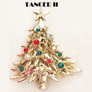 May include: Gold-tone Christmas tree brooch with red, green, and clear rhinestones. The brooch features a star on top and is decorated with a variety of colorful stones.