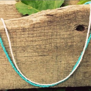 May include: A turquoise and white beaded necklace on a wooden surface.