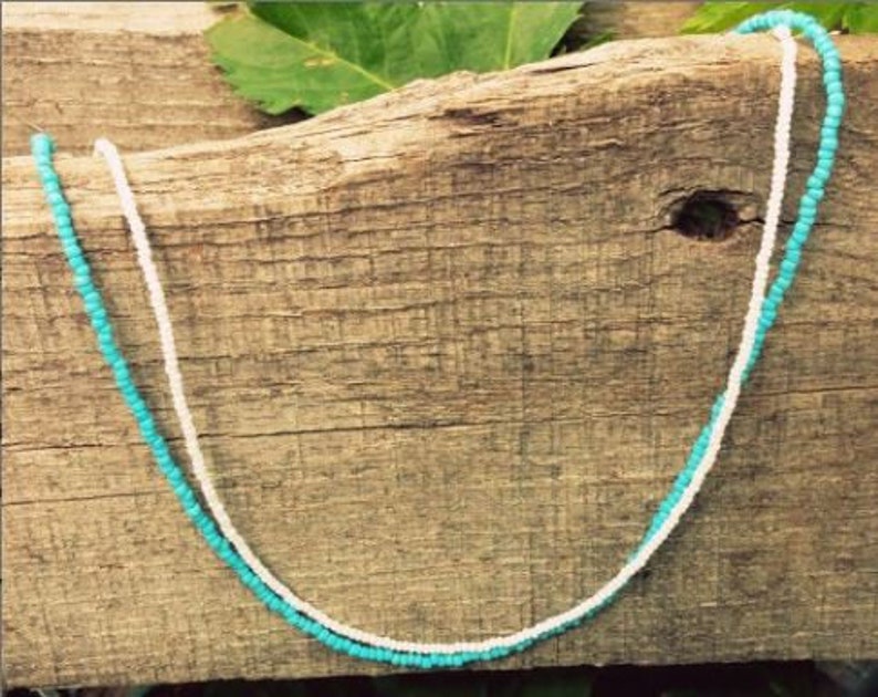 May include: A turquoise and white beaded necklace on a wooden surface.