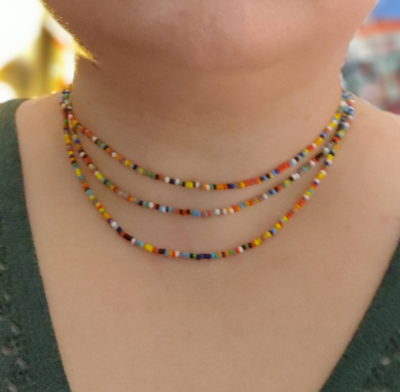 May include: A multi-layered necklace made of small, colorful beads. The beads are in shades of red, orange, yellow, green, blue, and white.