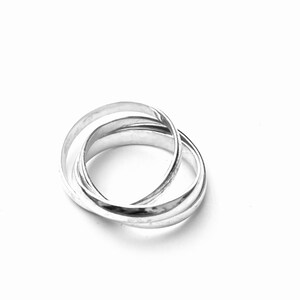 May include: A silver interlocking ring set. The rings are smooth and polished.
