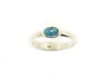 Può includere: Un anello d'argento con una pietra ovale turchese incastonata al centro.
