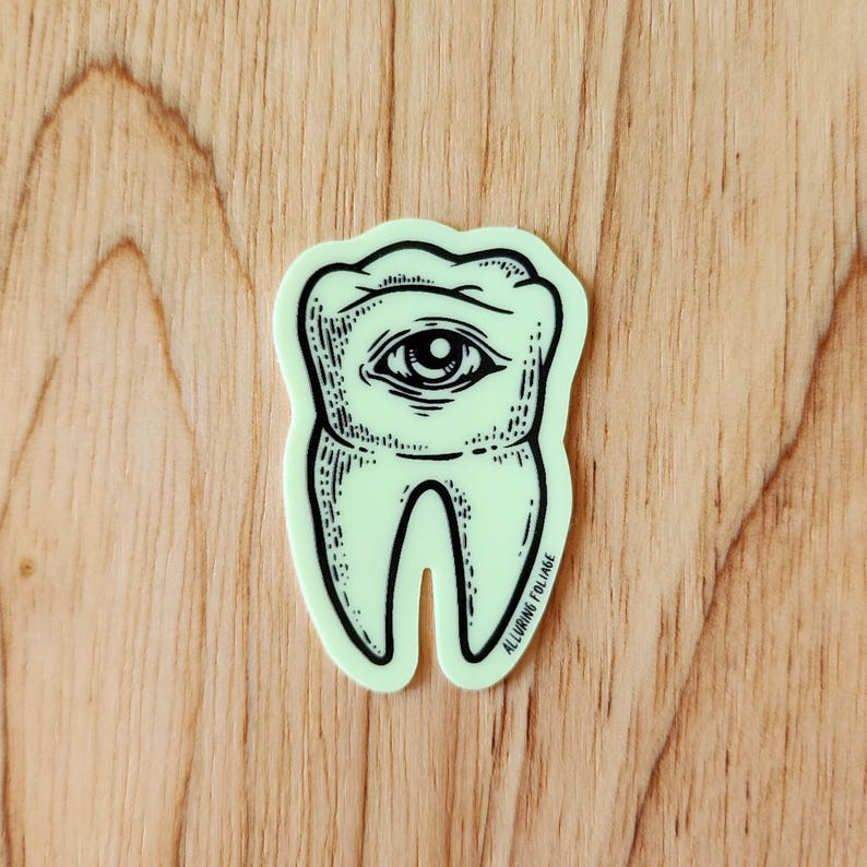May include: A green glow-in-the-dark sticker of a tooth with an eye in the center. The sticker has the text "Alluring Collage" at the bottom.