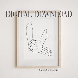 May include: A black and white line drawing of two hands intertwined, with the word "goodness" written on the arm. The artwork is framed in a light wood frame.