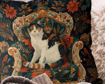 Puede incluir: Una almohada de tiro con un fondo azul oscuro que presenta un gato calico sentado en un sillón con estampado floral. La almohada tiene un diseño detallado con intrincados patrones florales y un ribete dorado.