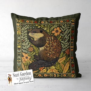 Könnte beinhalten: Ein grünes Kissen mit einem braunen und orangefarbenen Biber, umgeben von Blumen und Blättern. Das Kissen hat einen grünen Rand mit einem floralen Muster. Der Text "Suzi Gordon by FabFunky" befindet sich auf einem weißen Etikett in der linken unteren Ecke.