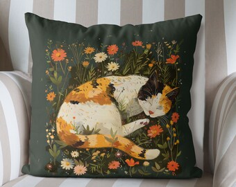 May include: A green throw pillow with a calico cat sleeping in a field of flowers. The cat is orange, white, and black. The flowers are yellow, orange, and red.