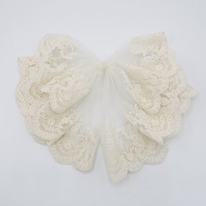 May include: A white lace collar with a ruffled edge. The collar is made of delicate, intricate lace and is perfect for adding a touch of elegance to any outfit.