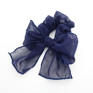 May include: A navy blue hair scrunchie with a large bow. The scrunchie is made of soft, sheer fabric.
