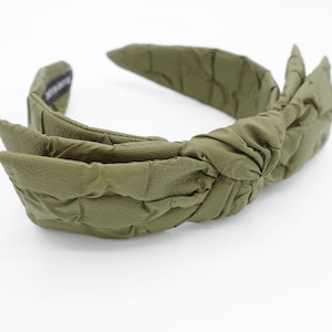 May include: A green quilted headband with a large bow. The headband is made of a soft, comfortable material and is perfect for adding a touch of style to any outfit.