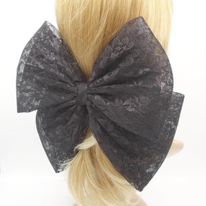 Könnte beinhalten: Ein großer schwarzer Spitzenhaar-Clip. Die Schleife ist zu einem großen, vollen Knoten gebunden und aus zarter schwarzer Spitze gefertigt.