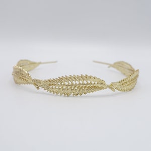 May include: A gold leaf headband with a delicate design. The headband is made of metal and has a simple, elegant look.