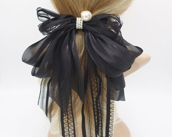 May include: Black sheer ribbon hair bow with a pearl accent. The bow is tied in a large, loose knot and has a long, flowing tail.