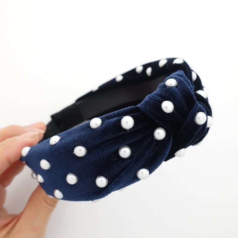 May include: A navy blue velvet headband with a knotted design and white pearl embellishments.