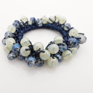 Peut inclure: Un élastique à cheveux bleu et blanc avec des perles. Les perles sont un mélange de perles transparentes et blanches opaques.