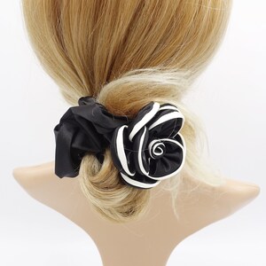 May include: Black and white satin flower hair scrunchie. The flower is made of multiple layers of fabric and has a white outline.