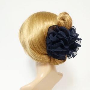 May include: A navy blue fabric flower hair clip. The clip is made of soft, ruffled fabric and is designed to hold hair in place.