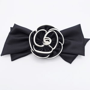 May include: A black satin bow with a large white and black fabric rose in the center.