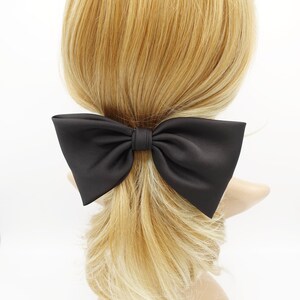 Op de afbeelding: Een grote zwarte satijnen strik haarclip. De strik is in een klassieke vorm geknoopt met twee lussen en een knoop in het midden.