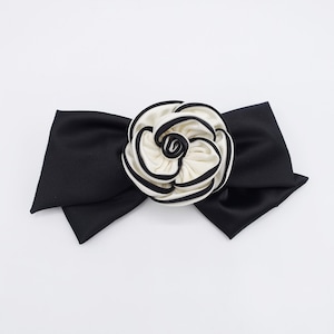 May include: A black satin bow with a white and black fabric rose in the center.
