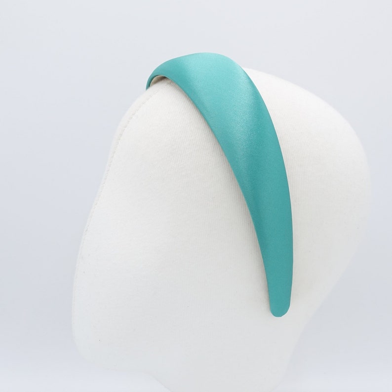 May include: A teal satin headband is displayed on a white mannequin head. The headband is a solid color and has a smooth, shiny texture. The headband is approximately 1 inch wide.