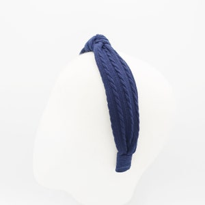 May include: A navy blue knitted headband with a knotted design.