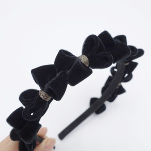 May include: Black velvet headband with multiple bows and gold accents.