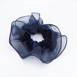 May include: A navy blue scrunchie with a velvet center and sheer, ruffled edges. This hair accessory adds a touch of elegance. The scrunchie is a stylish addition to any hairstyle.