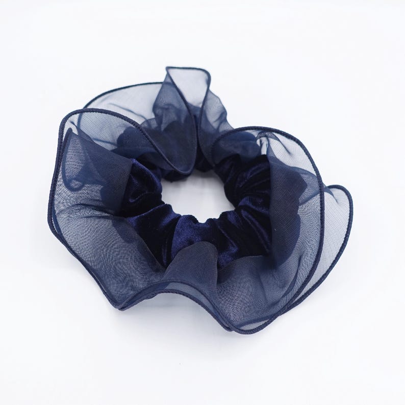 May include: A navy blue scrunchie with a velvet center and sheer, ruffled edges. This hair accessory adds a touch of elegance. The scrunchie is a stylish addition to any hairstyle.