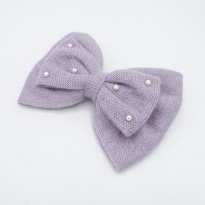 May include: A lavender knitted hair bow with pearl embellishments.