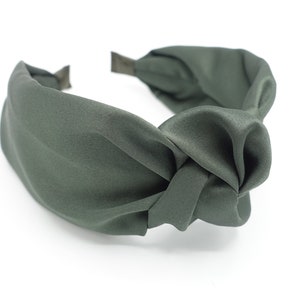 Puede incluir: Una diadema anudada de color verde oscuro hecha de tela de satén.
