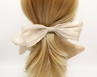 May include: A large, ivory-colored satin bow hair tie. The bow is tied in a classic shape with a single loop in the center.