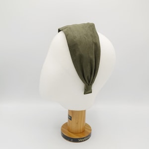 May include: A dark green fabric headband on a white mannequin head. The headband is made of a soft, stretchy material and is designed to be worn around the head.
