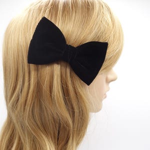 May include: A black velvet bow hair clip. The bow is tied in a classic shape and is attached to a metal clip.
