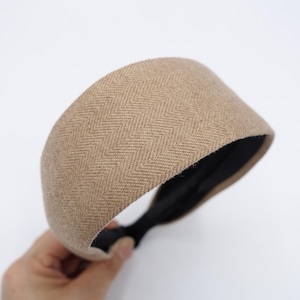 Peut inclure: Un serre-tête marron avec un motif en chevrons. Le serre-tête est fait d'un tissu doux et texturé et a un élastique noir.