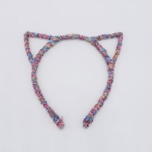 Puede incluir: Una diadema de orejas de gato colorida hecha de oropel brillante e iridiscente. La diadema es rosa, azul y verde.