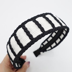 May include: Black and white headband with a braided design. The headband is made of a soft, stretchy material and has a comfortable fit.