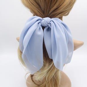 May include: A light blue chiffon hair bow with a large bow at the back. The bow is tied around a ponytail.