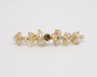 May include: A gold hair clip with clear and brown crystals.